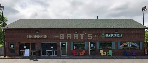 A brick building with two restaurants: Bart's Luncheonette and Beanery Bistro, featuring colorful chairs outside.