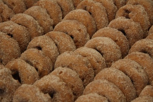 A close-up of rows of sugar-coated donuts arranged neatly in a display.