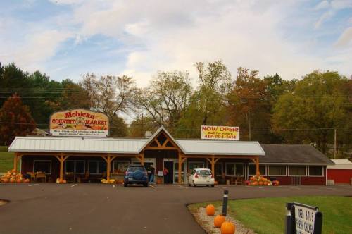 Exterior of Mohican Country Market with pumpkins in front, featuring "Now Open" signs and a welcoming entrance.