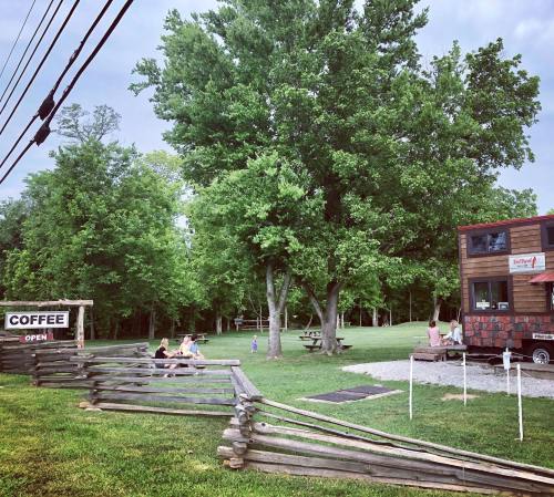 A cozy coffee shop with outdoor seating, surrounded by trees and a grassy area, inviting visitors to relax.