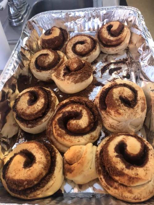 A tray of freshly baked cinnamon rolls with swirls of cinnamon and sugar, golden brown and fluffy.