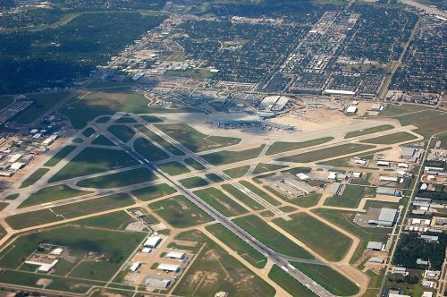 Aerial view of an airport with runways, taxiways, and surrounding urban areas.
