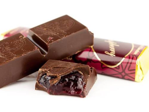 Close-up of chocolate bars with a piece broken open, revealing a rich berry filling inside.