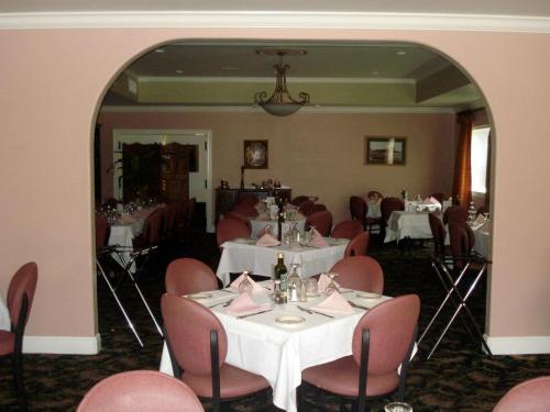 A dining room with neatly set tables, pink napkins, and elegant decor, featuring arched entryways and soft lighting.