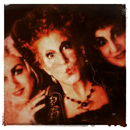 Three women with dramatic makeup and hairstyles pose playfully, showcasing a whimsical and theatrical vibe.