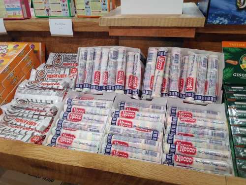 A wooden shelf filled with various packs of Necco wafers and French Chew candies.