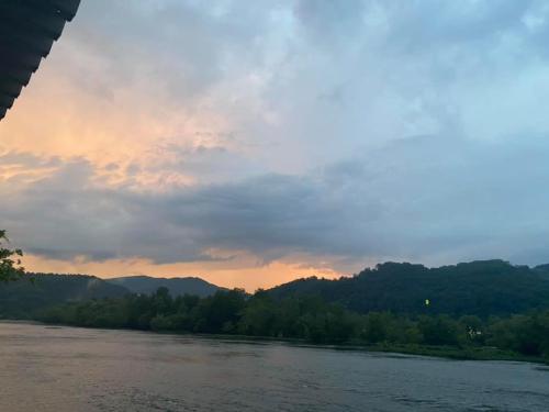 A serene river scene at sunset, with mountains and clouds reflecting soft colors in the sky.