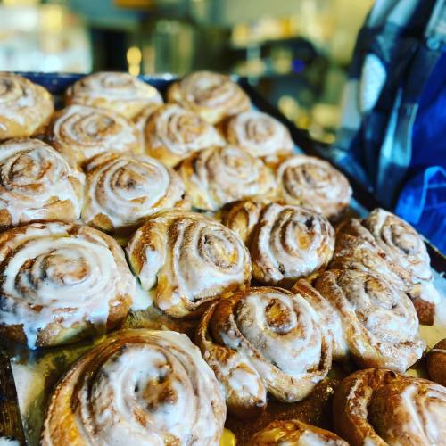 A tray of freshly baked cinnamon rolls drizzled with icing, showcasing their golden-brown swirls.