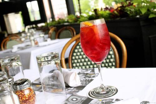 A refreshing red drink with ice and an orange slice, placed on a table set with glassware and napkins.