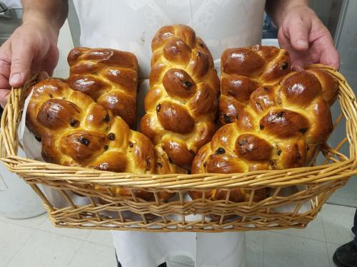 A person holds a basket filled with freshly baked, golden-brown braided challah bread.