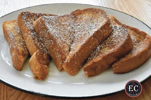 A plate of golden-brown French toast slices dusted with powdered sugar.