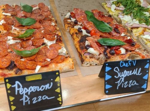 Two types of pizza on display: one topped with pepperoni and the other with salami, olives, and fresh basil.