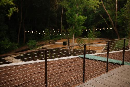 A view of a park with string lights in the background, seen from a railing on a patio.