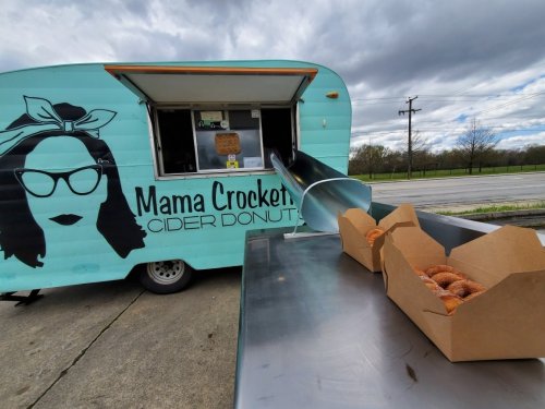 A food truck named "Mama Crockett's" serves cider donuts, with a box of donuts on a table in front.