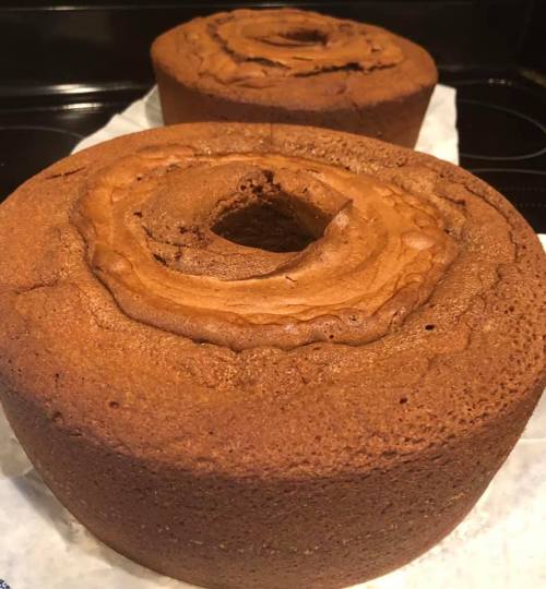 Two round, baked cakes with a central hole, resting on parchment paper against a dark background.