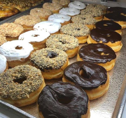 A display of assorted donuts, including chocolate frosted, white frosted, and nut-covered varieties.