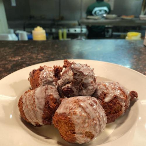 A plate of glazed doughnut holes with a blurred kitchen background.