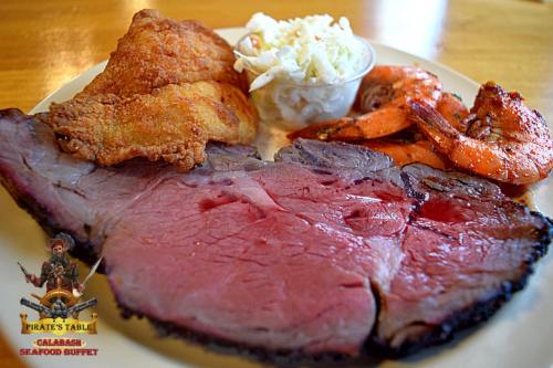 A plate featuring sliced roast beef, fried shrimp, and coleslaw, served at a seafood buffet.