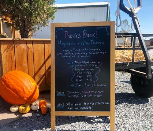 A sign advertising hayrides and wine tastings, with details on pricing, dates, and reservation instructions.