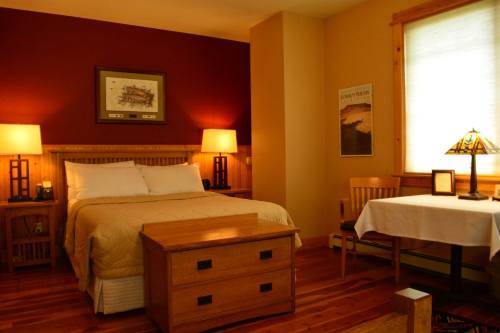 Cozy bedroom with a wooden bed, warm lighting, and a small dining table by the window.
