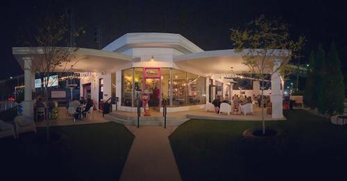 A modern restaurant at night, featuring large windows, outdoor seating, and a cozy atmosphere.