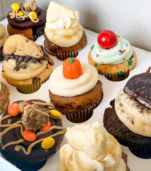 A variety of colorful cupcakes with different toppings, including cookies, frosting, and seasonal decorations.