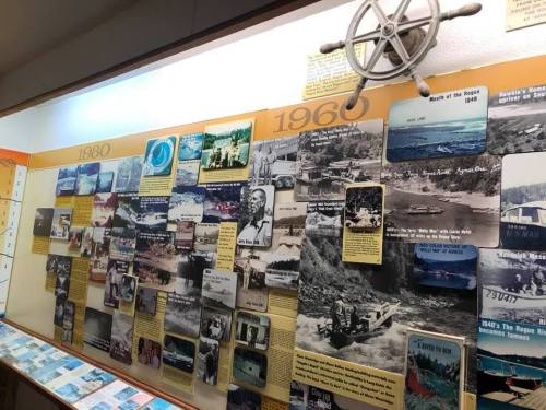 A display wall featuring historical photos and information from the 1960s to 1980s, including a ship's wheel.