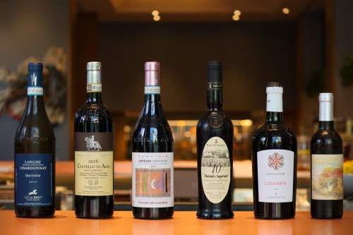 A selection of six wine bottles displayed on a wooden counter in a restaurant setting.