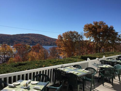 A scenic view of a lake surrounded by autumn trees, with outdoor dining tables set on a sunny day.