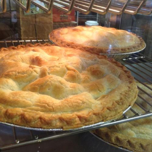 Two golden-brown pies cooling on a wire rack inside an oven.