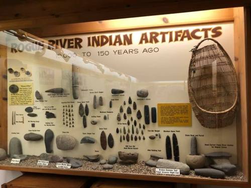 Display of Rogue River Indian artifacts, showcasing tools and items from 1000 to 150 years ago, with a woven basket.