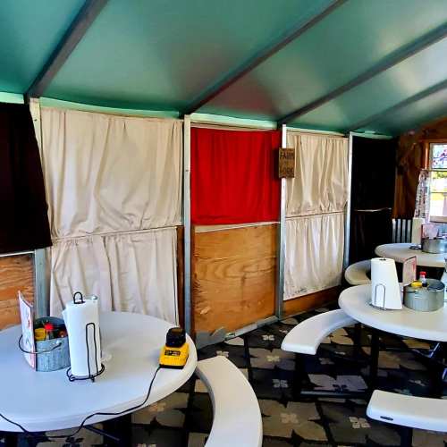 Interior of a casual dining space with tables, curtains, and a colorful wall, featuring a cozy, inviting atmosphere.