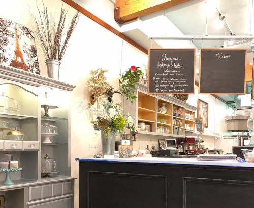 Cozy café interior with a display case, chalkboard menus, and decorative flowers, featuring a Parisian theme.