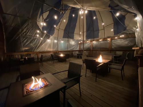 Cozy outdoor seating area under a tent, featuring string lights and fire pits on wooden decking.