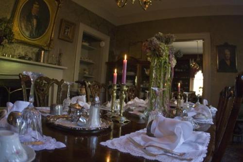 A beautifully set dining table with candles, floral arrangements, and vintage tableware in an elegant room.