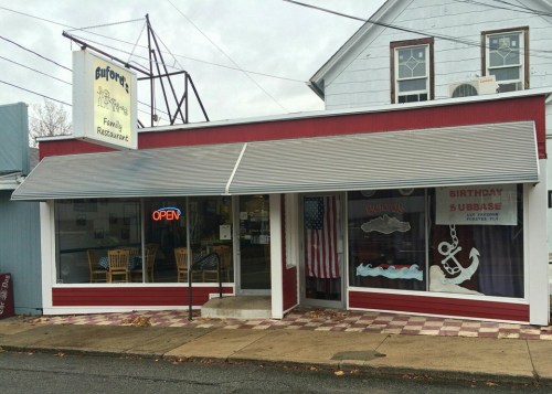 A small family restaurant with a red exterior, open sign, and awning, featuring nautical decor and an American flag.