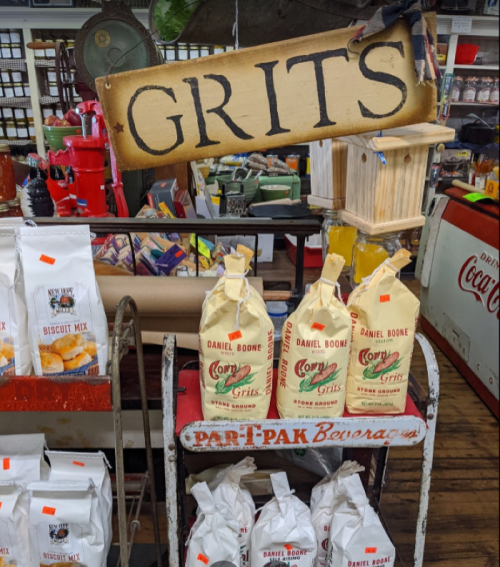 A display of bags labeled "Grits" and "Biscuit Mix" in a rustic store setting.