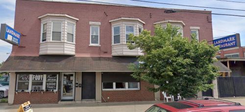 Exterior view of a brick building with bay windows, featuring a restaurant sign and a storefront below.