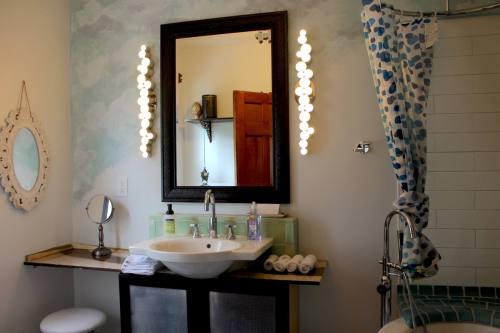 A modern bathroom featuring a sink, mirror, decorative lights, and a shower curtain with a blue pattern.