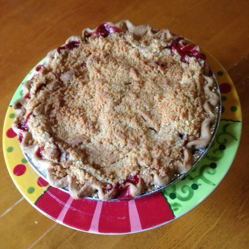 A freshly baked pie with a crumbly topping, sitting on a colorful plate.