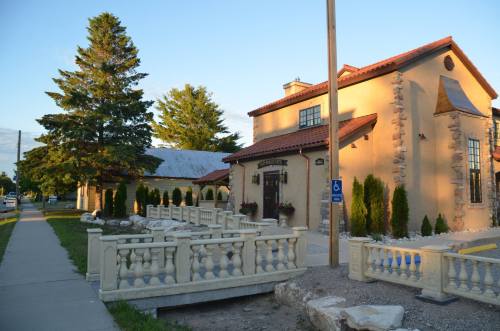 A charming building with a stone facade, surrounded by trees and a walkway, under a clear blue sky.