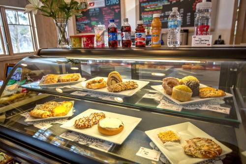 A display case filled with various pastries and drinks, including cakes, muffins, and bottled beverages.