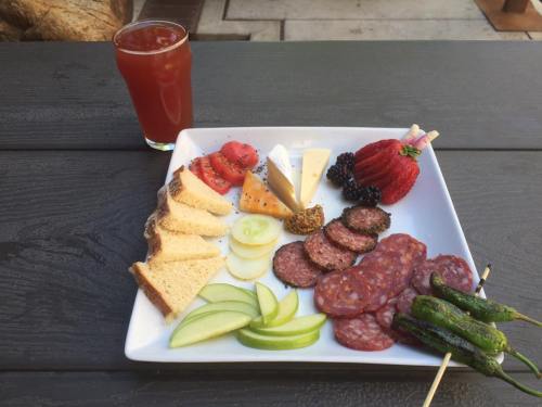 A platter of assorted meats, cheeses, fruits, and bread, accompanied by a drink, on a wooden table.