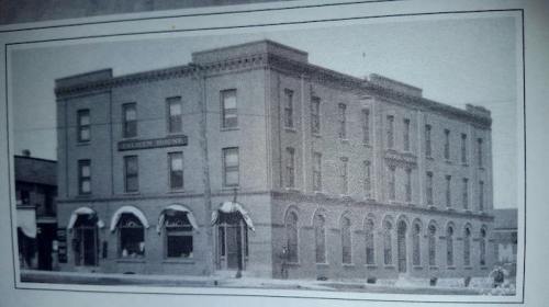 Historic black-and-white photo of a three-story brick building with arched windows and a sign reading "Hotel."