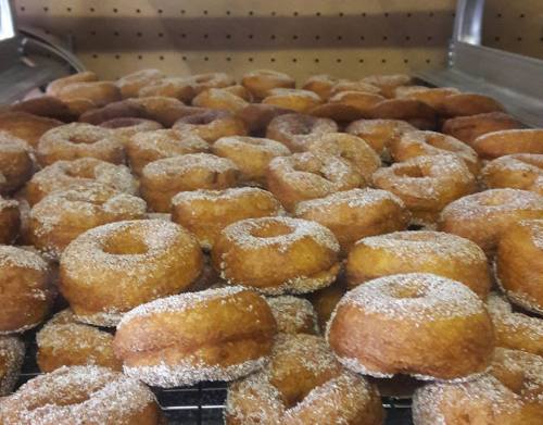 A close-up of freshly made donuts dusted with sugar, arranged neatly on a cooling rack.