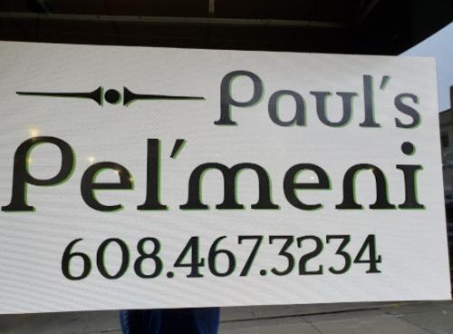 Sign for "Paul's Pel'meni" with a phone number, displayed outdoors.