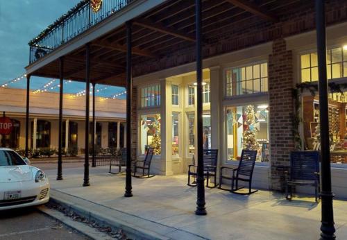 A charming storefront decorated for the holidays, featuring rocking chairs and festive lights in the evening.