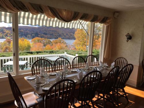 A dining table set for a meal, with a view of colorful autumn trees and a lake through large windows.