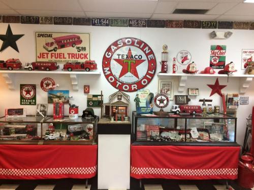 A vintage Texaco display featuring gas pumps, memorabilia, and a model truck in a retro-themed room.