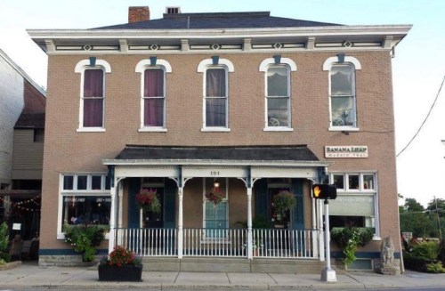 Historic brick building with white trim, large windows, and flower boxes, featuring a sign for "Banana Trip."